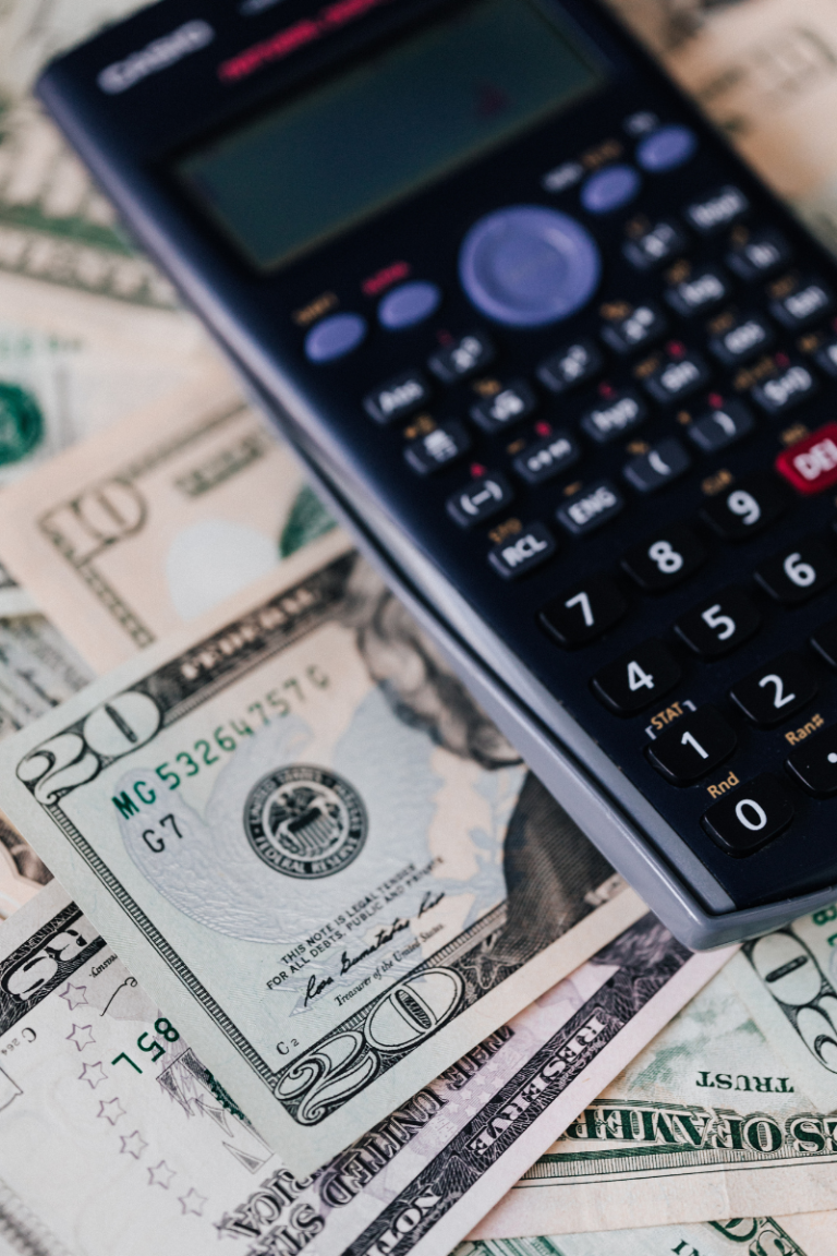 Photo of a black calculator on a pile of US $20 bills